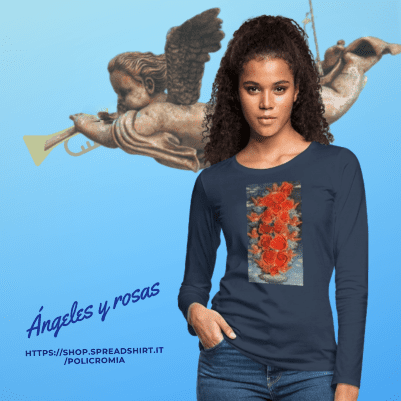 Una mujer vistiendo una camiseta de manga larga azul marino con el diseño "Ángeles y rosas", sobre un fondo celeste con la ilustración de un ángel tocando la trompeta.